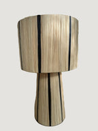 La lampe MALU incarne la simplicité raffinée et l’élégance naturelle.
Tissée à la main en raphia majoritairement naturel, rehaussée d’un fin filet noir, elle diffuse une lumière douce et chaleureuse, parfaite pour créer une ambiance cosy et apaisante.

Idéale en lampe de chevet, sur un buffet ou une console, MALU s’intègre harmonieusement dans tout intérieur bohème, contemporain ou ethnique chic.