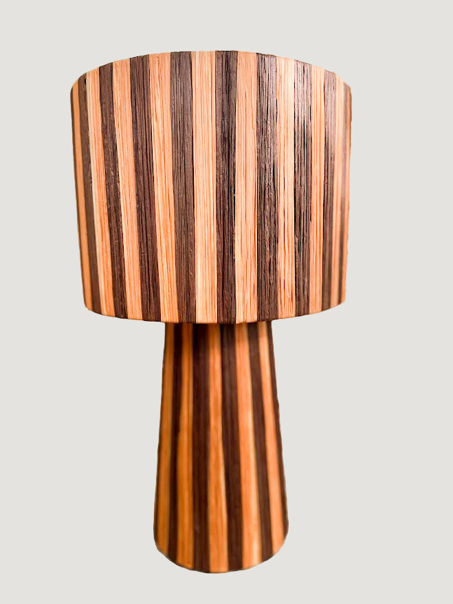 La lampe TERRA séduit par ses tons profonds d’orange et de cacao, qui diffusent une lumière douce et enveloppante.
Tissée à la main en raphia naturel, elle allie chaleur, authenticité et élégance contemporaine.