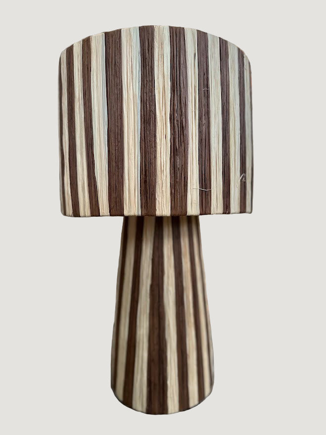 La lampe AMA associe avec élégance les tons cacao et naturel du raphia tissé à la main. Son jeu de nuances terreuses crée une lumière chaleureuse et apaisante, idéale pour une chambre, un salon ou un coin lecture.

Son design sobre et raffiné met en valeur la matière naturelle et le savoir-faire artisanal, faisant d’AMA une pièce intemporelle au charme discret.