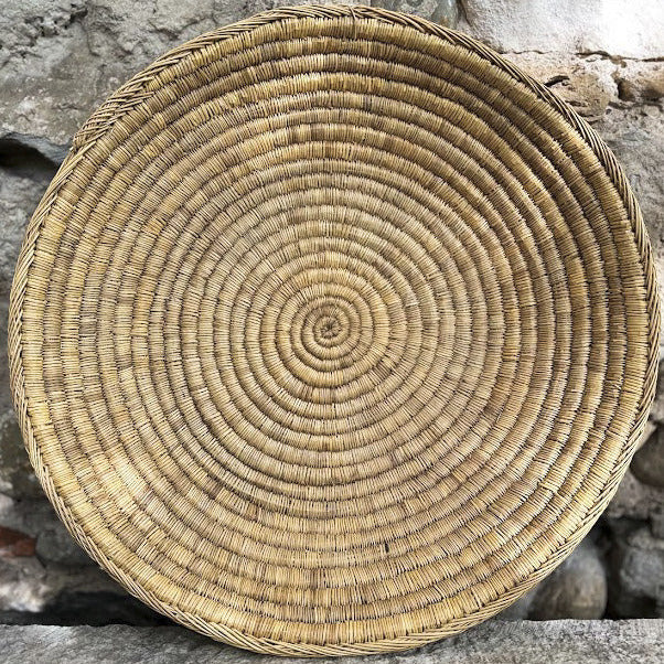 Le grand plateau BERBI incarne tout le charme de l’artisanat berbère. Réalisé à la main en fibres naturelles tressées, il se distingue par son diamètre généreux de 50 cm, idéal pour habiller une table, servir de corbeille à fruits, ou simplement en décoration murale.