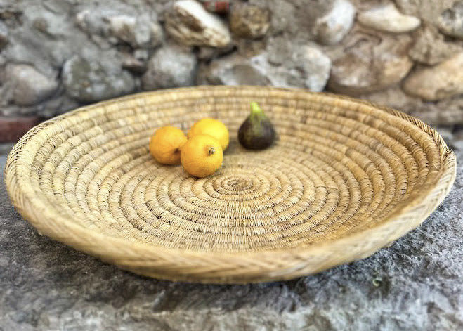 Le grand plateau BERBI incarne tout le charme de l’artisanat berbère. Réalisé à la main en fibres naturelles tressées, il se distingue par son diamètre généreux de 50 cm, idéal pour habiller une table, servir de corbeille à fruits, ou simplement en décoration murale.