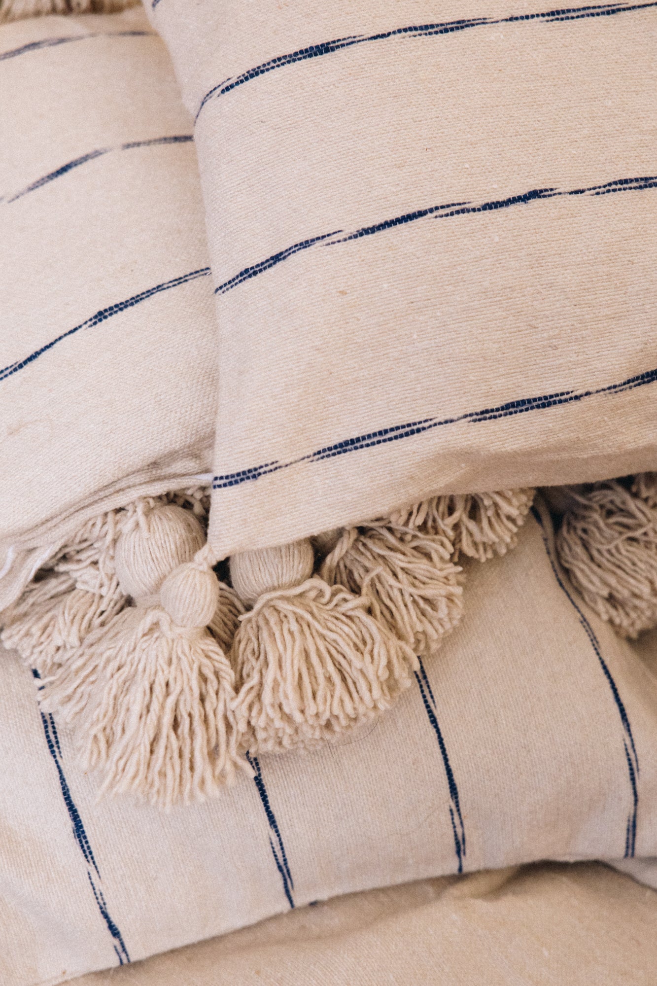 Tissé et confectionné à la main en coton brut sur un métier traditionnel marocain, le plaid INDIRA apporte caractère et authenticité à votre intérieur.

Son élégance réside dans ses rayures indigo sur fond écru, intemporels et raffinés.
Ses finitions soignées, rehaussées de pompons, en font une pièce chaleureuse et unique.