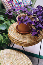 La table TAWU incarne la rencontre parfaite entre artisanat traditionnel et design contemporain.
Tressée à la main à partir de feuilles de palmier naturelles, chaque pièce révèle un travail minutieux et une texture organique unique. Son piètement en métal noir brut apporte une touche moderne et élégante, créant un contraste subtil et harmonieux.