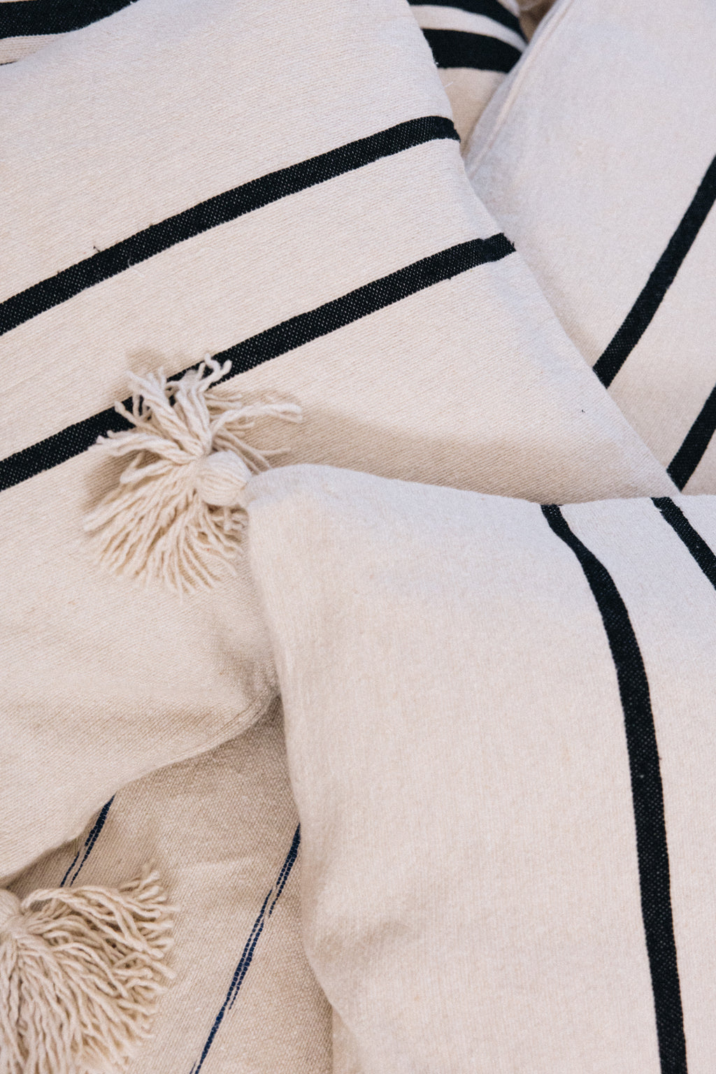 En coton brut tissé et confectionné à la main sur un métier traditionnel marocain, la housse ALMARE séduit par son élégance épurée.
Ses rayures noires sur fond écru apportent une touche authentique et intemporelle à votre décoration.