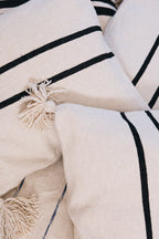 En coton brut tissé et confectionné à la main sur un métier traditionnel marocain, la housse ALMARE séduit par son élégance épurée.
Ses rayures noires sur fond écru apportent une touche authentique et intemporelle à votre décoration.