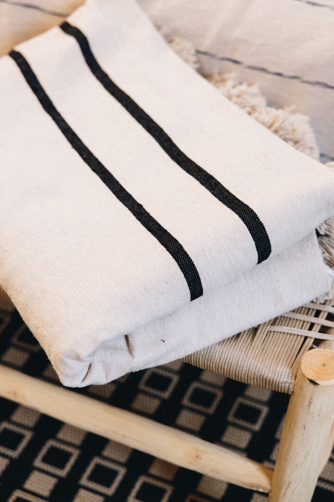 Tissé et confectionné à la main en coton brut sur un métier traditionnel marocain, le plaid ALMA apporte caractère et authenticité à votre intérieur.

Son élégance réside dans ses jeux de rayures noires sur fond écru, intemporels et raffinés.
Ses finitions soignées, rehaussées de pompons en font une pièce chaleureuse et unique.