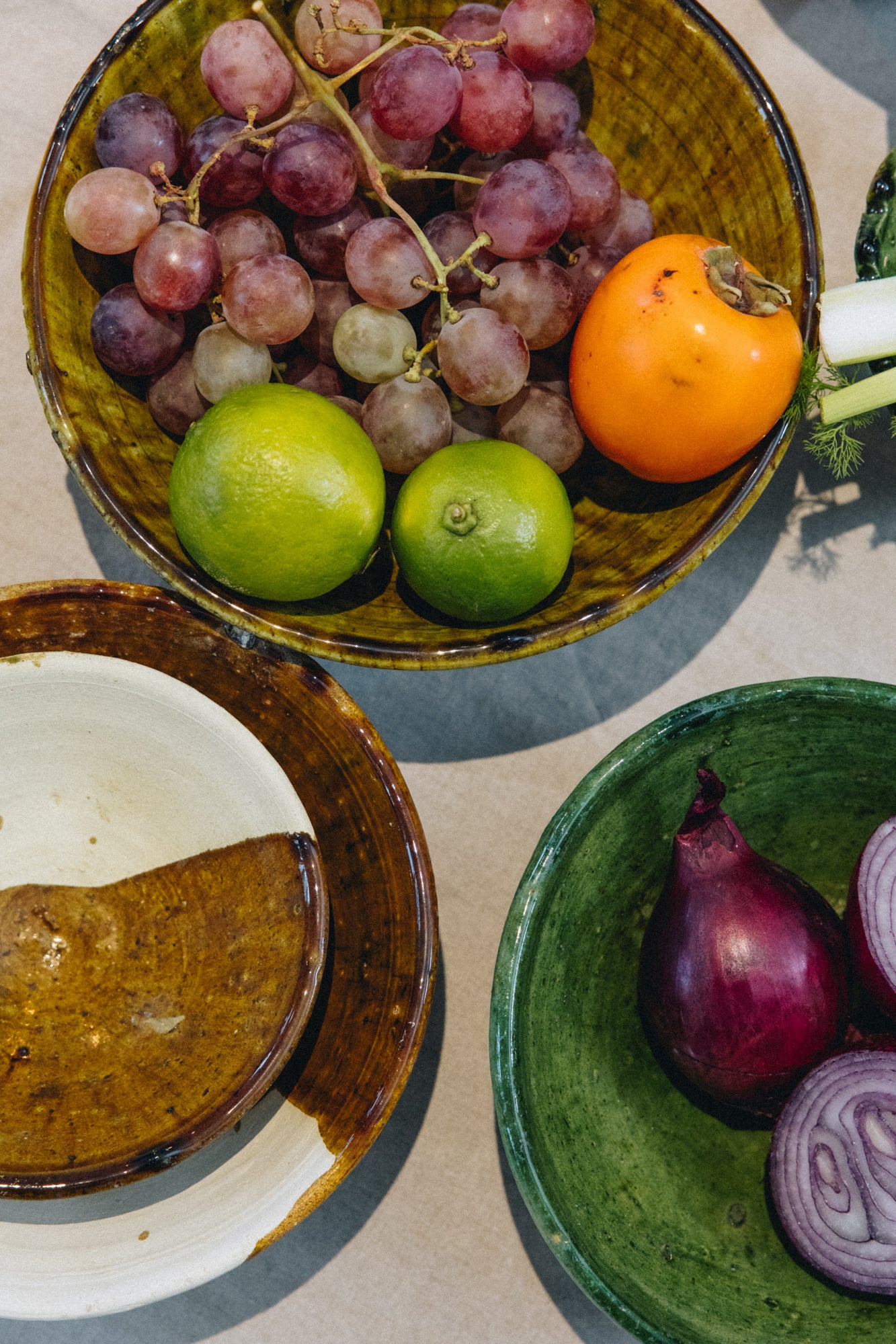 Façonné et émaillé à la main, le saladier AGA révèle un jeu de matières unique : une partie émaillée aux nuances ocre-vert, l’autre laissée volontairement brute, au naturel.