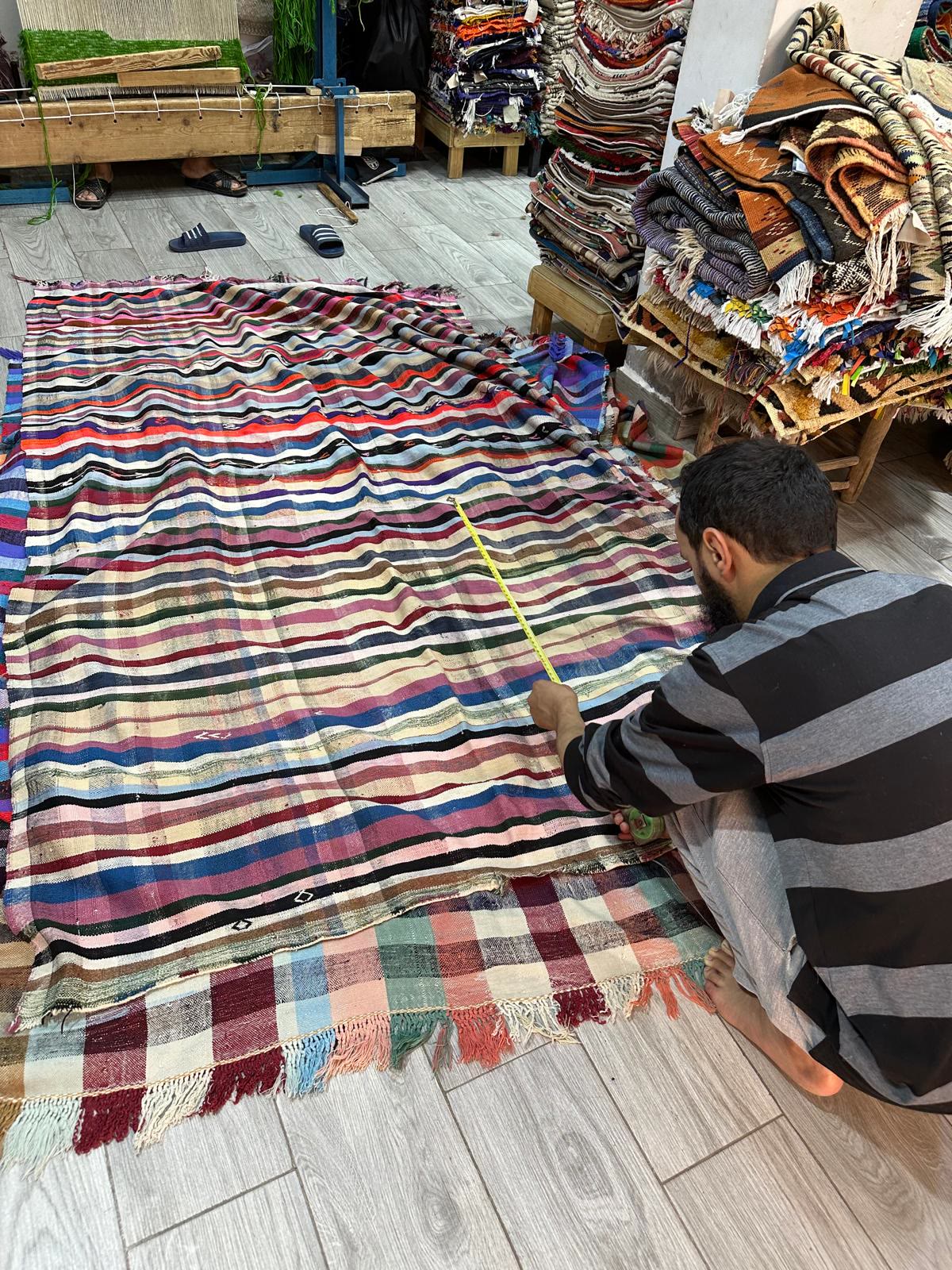 Artisan mesurant un kilim rayé à Marrakech
